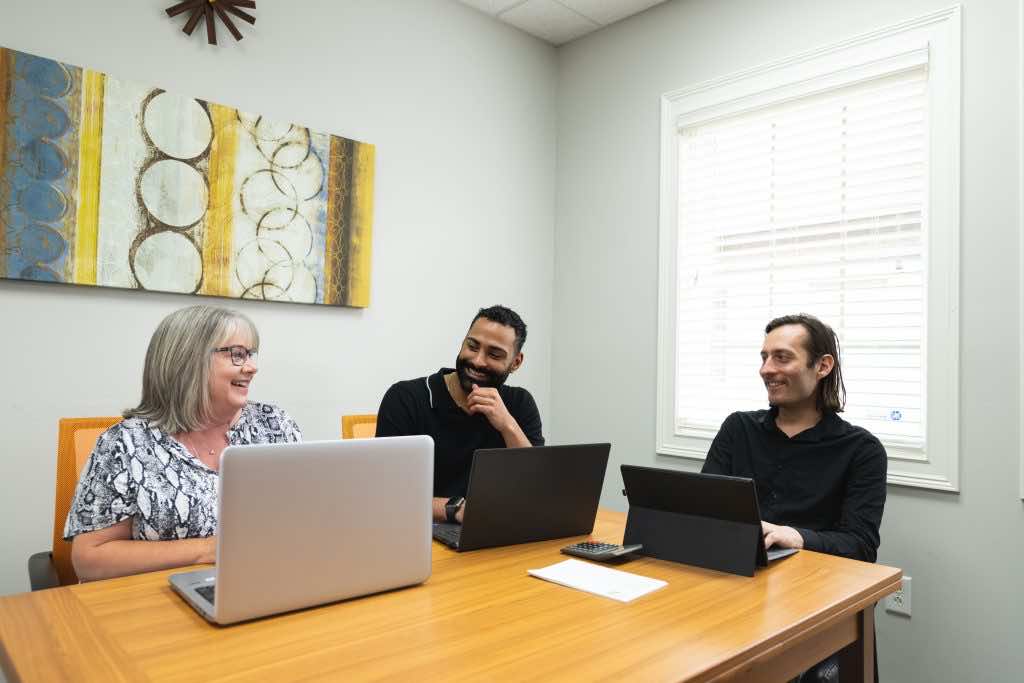 Three People Sitting at Table in Conference Room