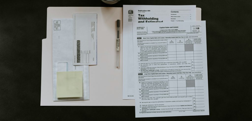 Individual Tax Documents in Manila Envelope with Envelope and Pen on Dark Colored Table Top