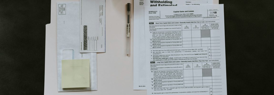 Individual Tax Documents in Manila Envelope with Envelope and Pen on Dark Colored Table Top